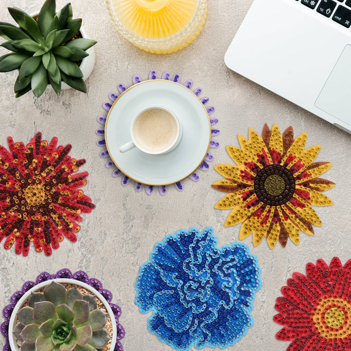 Colorful flower-shaped coasters on a table with a cup and laptop.