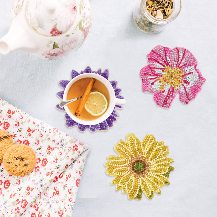 Floral coasters with a teacup, lemon, and cookies on a light blue surface