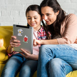 Woman and child sitting together on a yellow couch, looking at a tablet with Snoopy stickers.