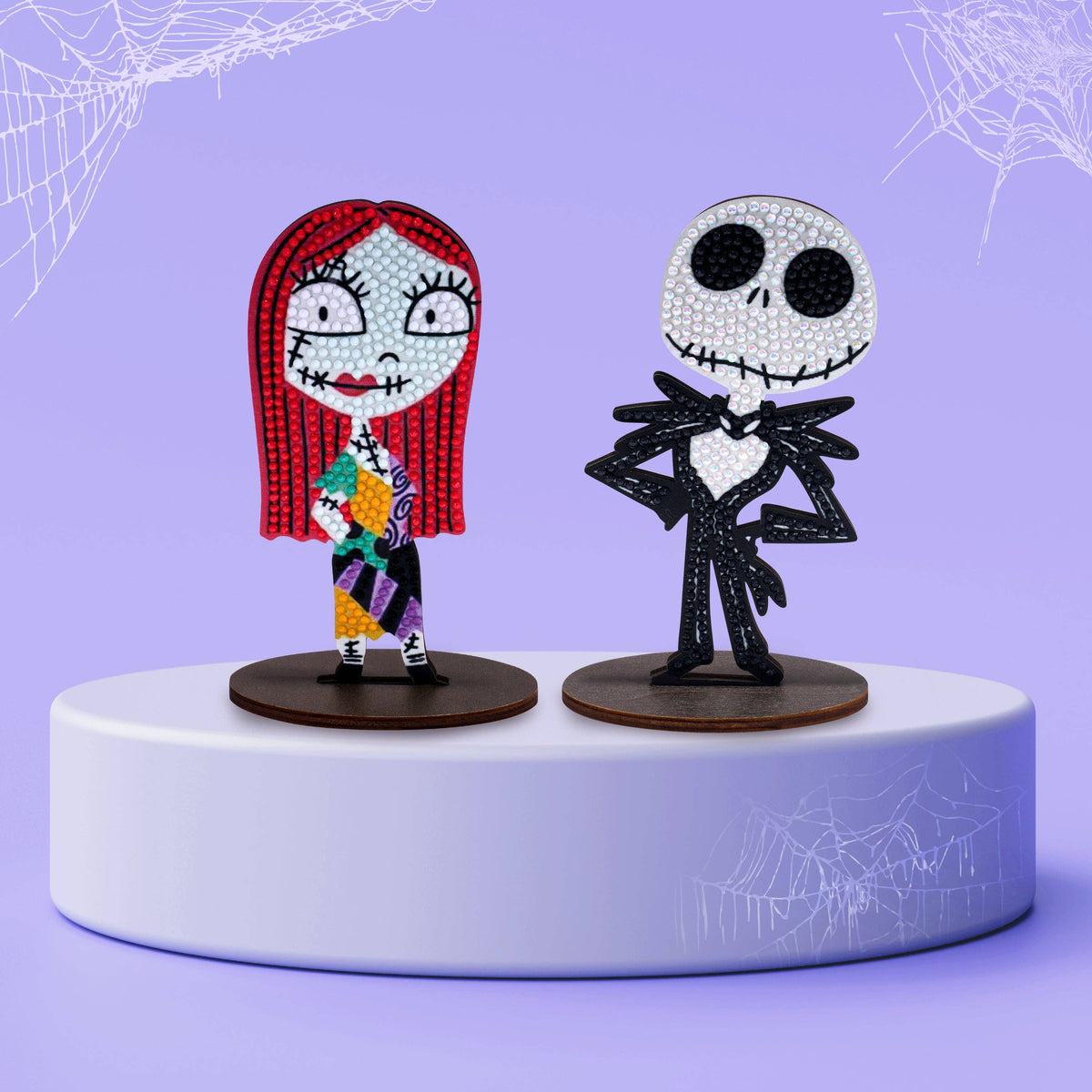 Two decorative The Nightmare Before Christmas Diamond Art figures of a character with red hair and another skeleton on a purple platform with spider web designs.