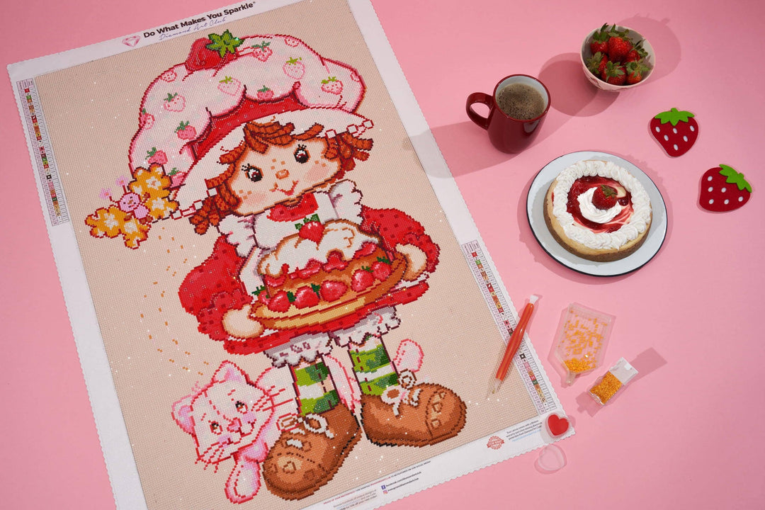 Cross-stitch pattern with a strawberry-themed character on a pink background