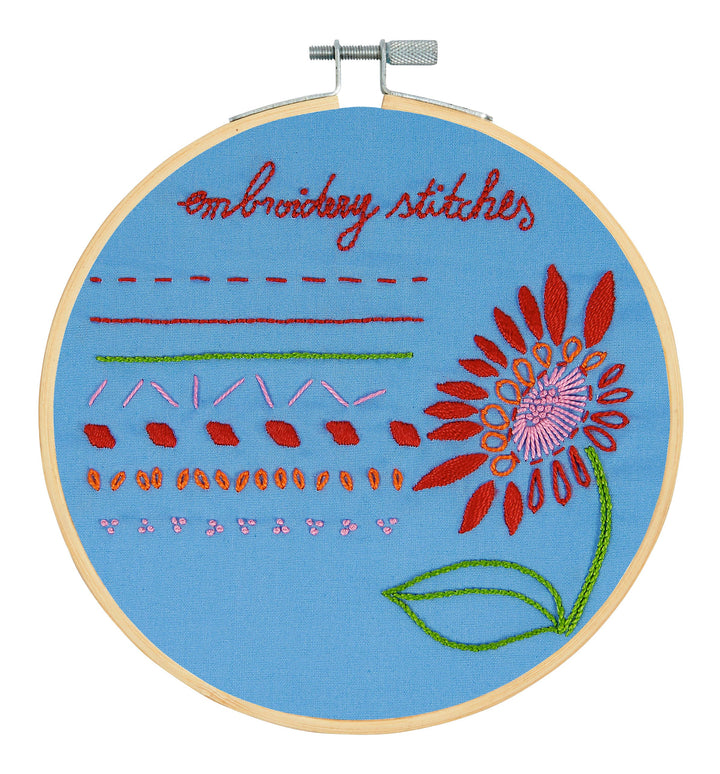 Embroidery hoop with floral design and text on a blue background