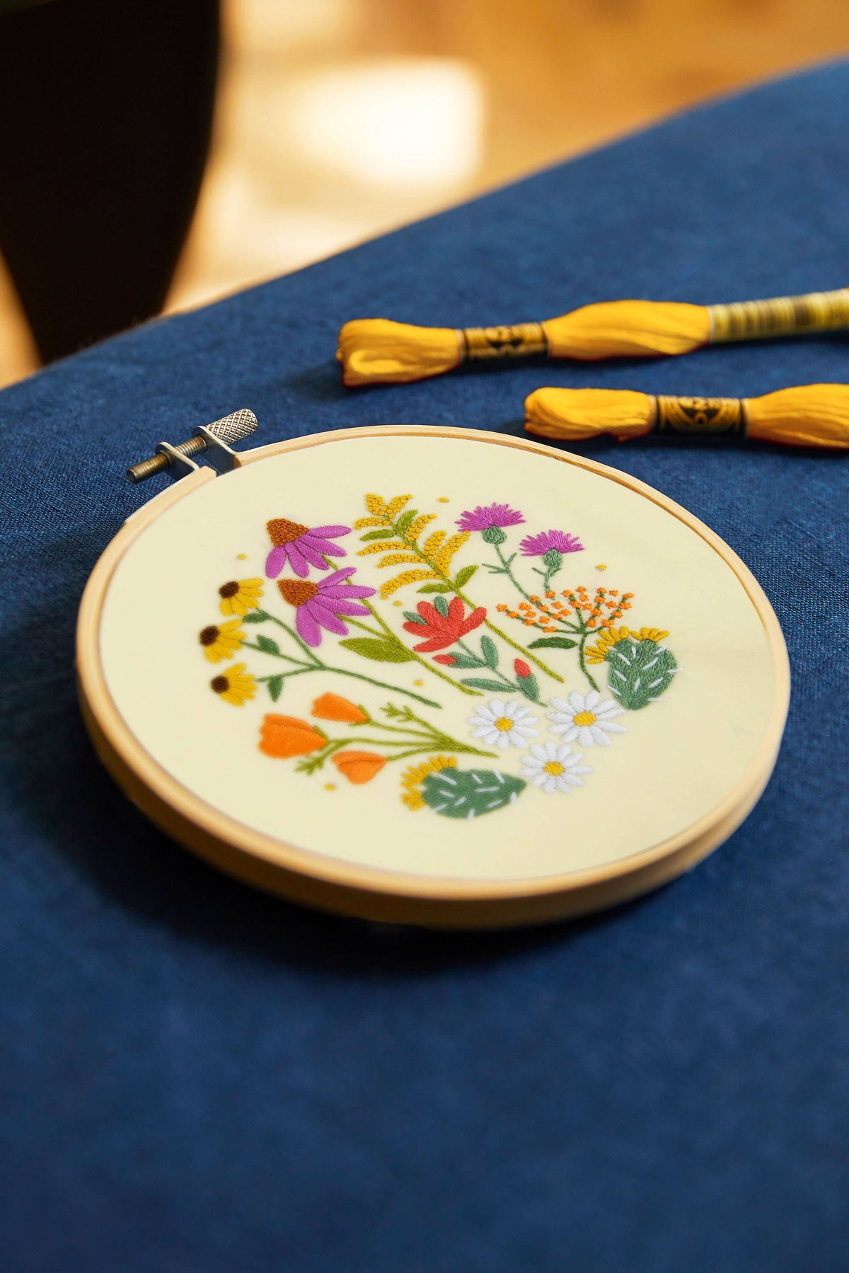 Embroidery hoop with floral design on a blue fabric background