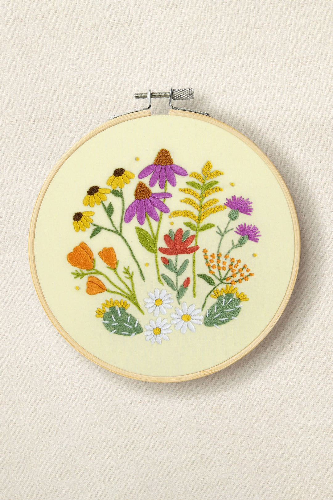 Embroidery hoop with colorful floral design on a beige background