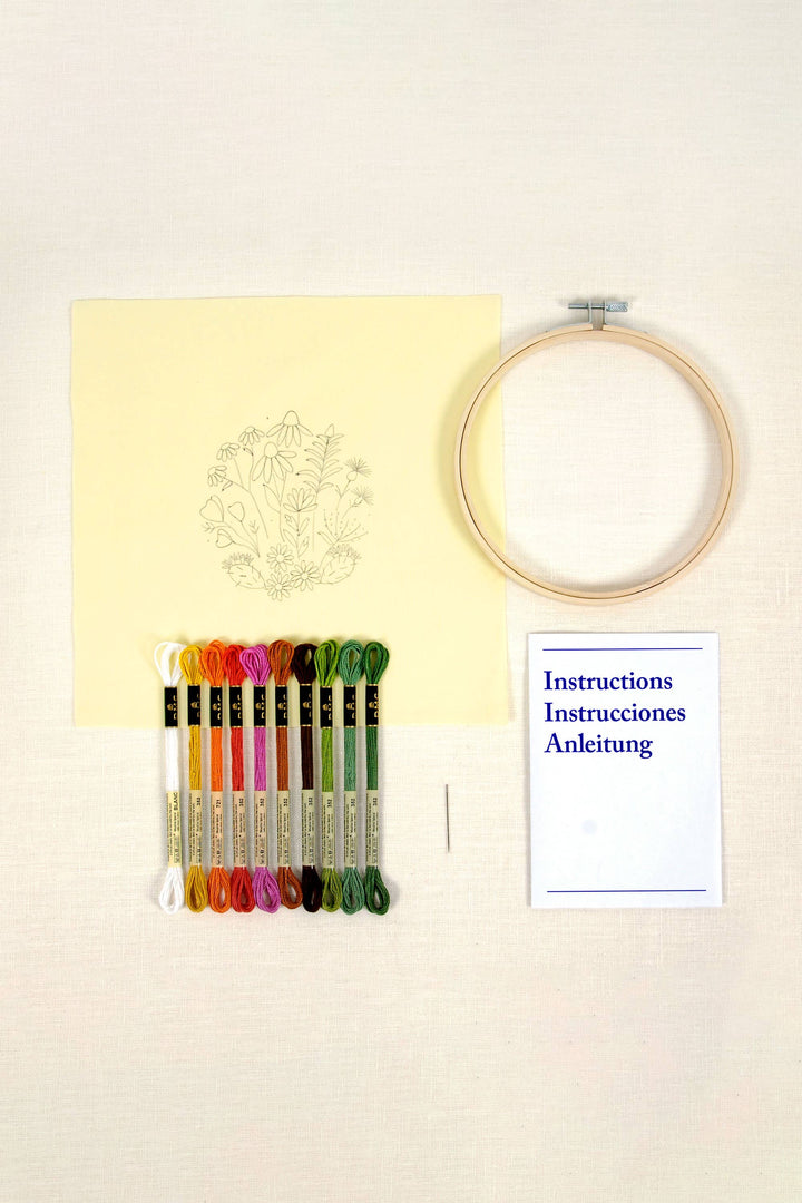 Embroidery hoop, colorful threads, and a chart on a light beige background