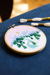 Embroidery hoop with a nature-themed design on a blue fabric background