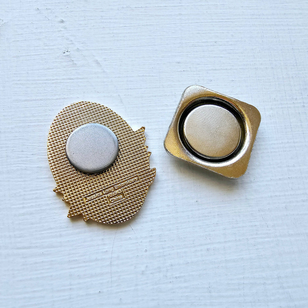 Two gold-colored metal buttons on a light blue textured background