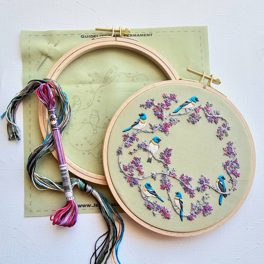 Embroidery hoop with bird and floral design on a white background