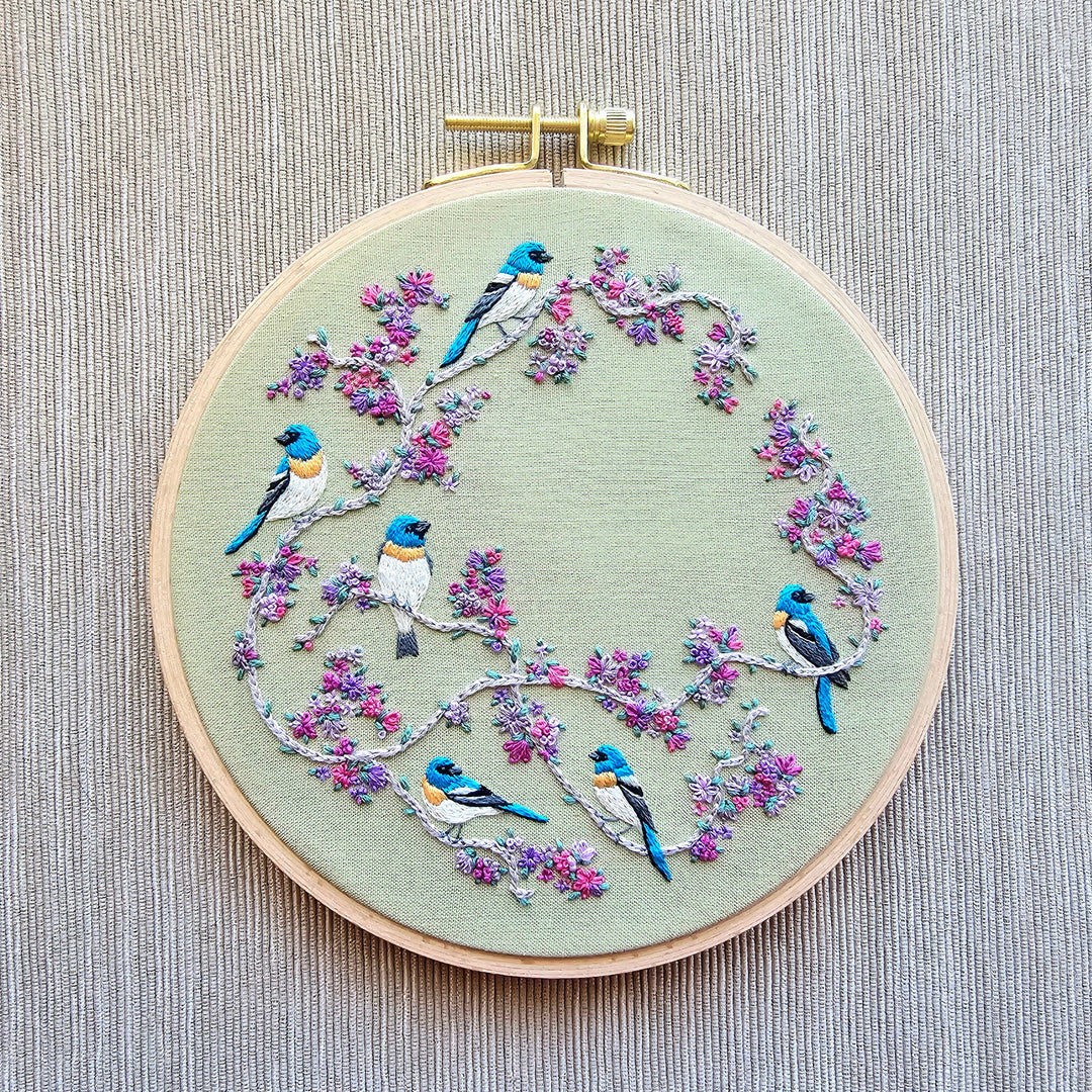 Embroidery hoop with birds and flowers on a textured fabric background