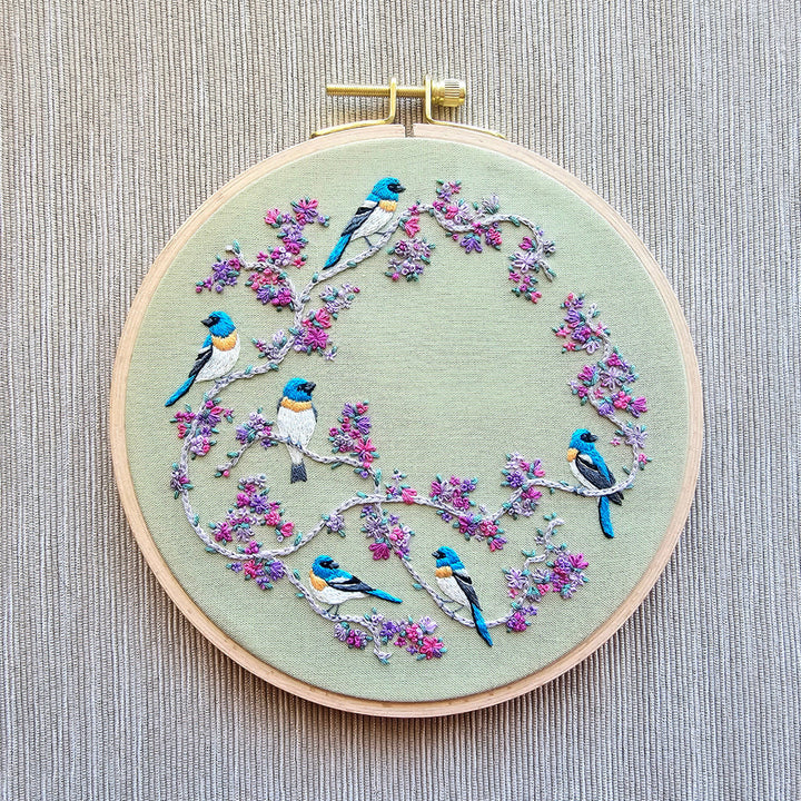 Embroidery hoop with birds and flowers on a textured fabric background