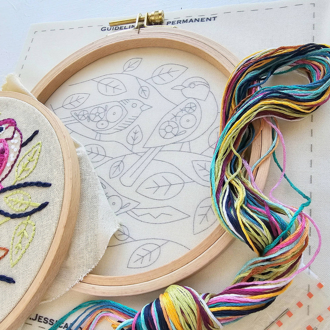 Embroidery hoops with colorful thread and designs on a light surface