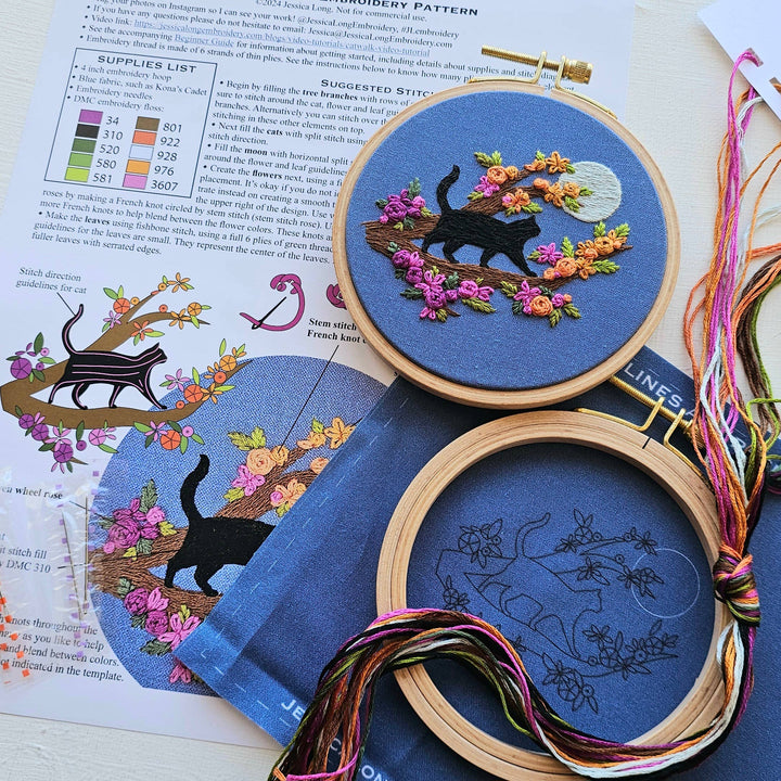 Embroidery hoops with cat and floral designs on a book page