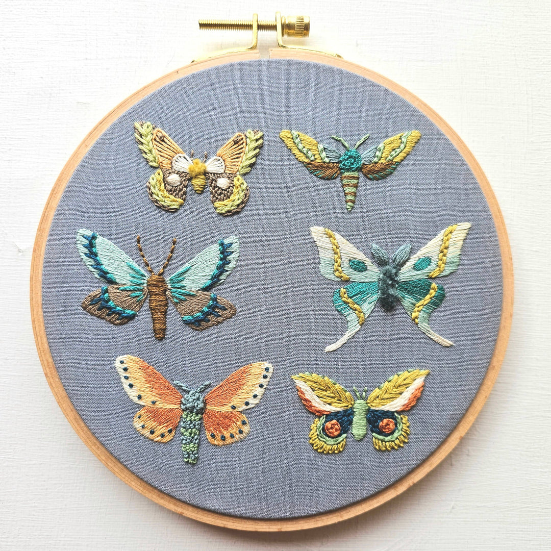 Embroidery hoop with embroidered butterflies on a gray fabric background