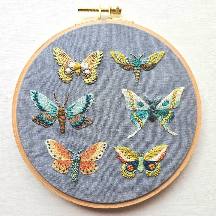 Embroidery hoop with embroidered butterflies on a gray fabric background