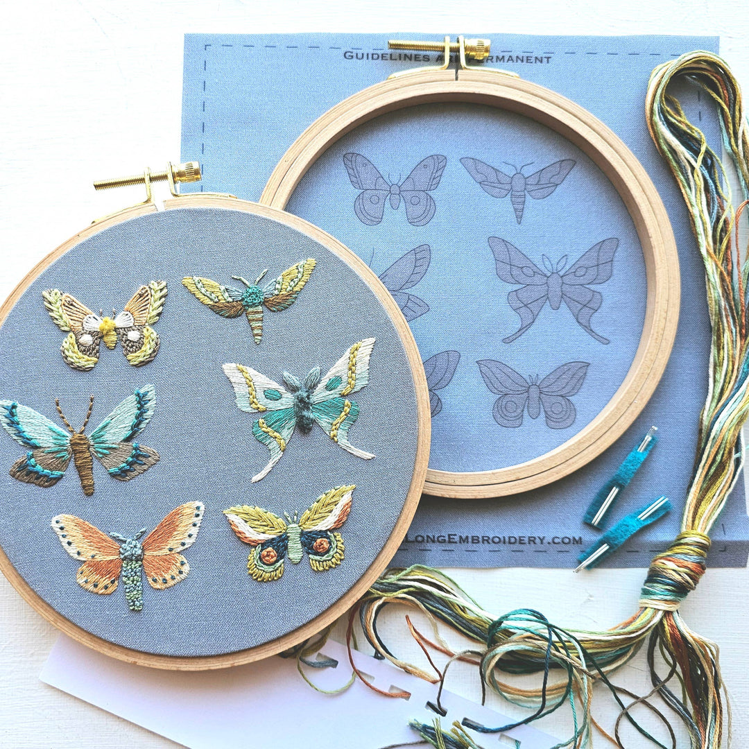 Embroidery hoop with embroidered butterflies and embroidery thread on a blue background