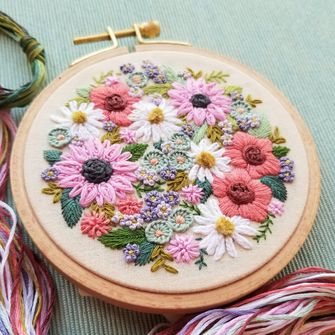 Embroidery hoop with colorful floral embroidery on a light green background