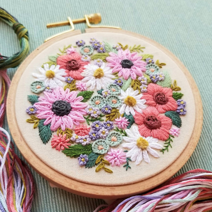 Embroidery hoop with colorful floral embroidery on a light green background