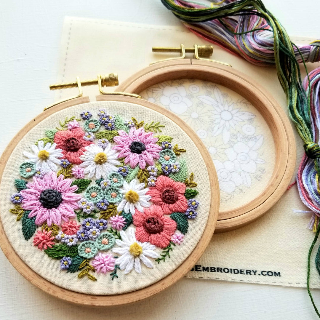 Embroidery hoop with floral design and colorful thread on a white background