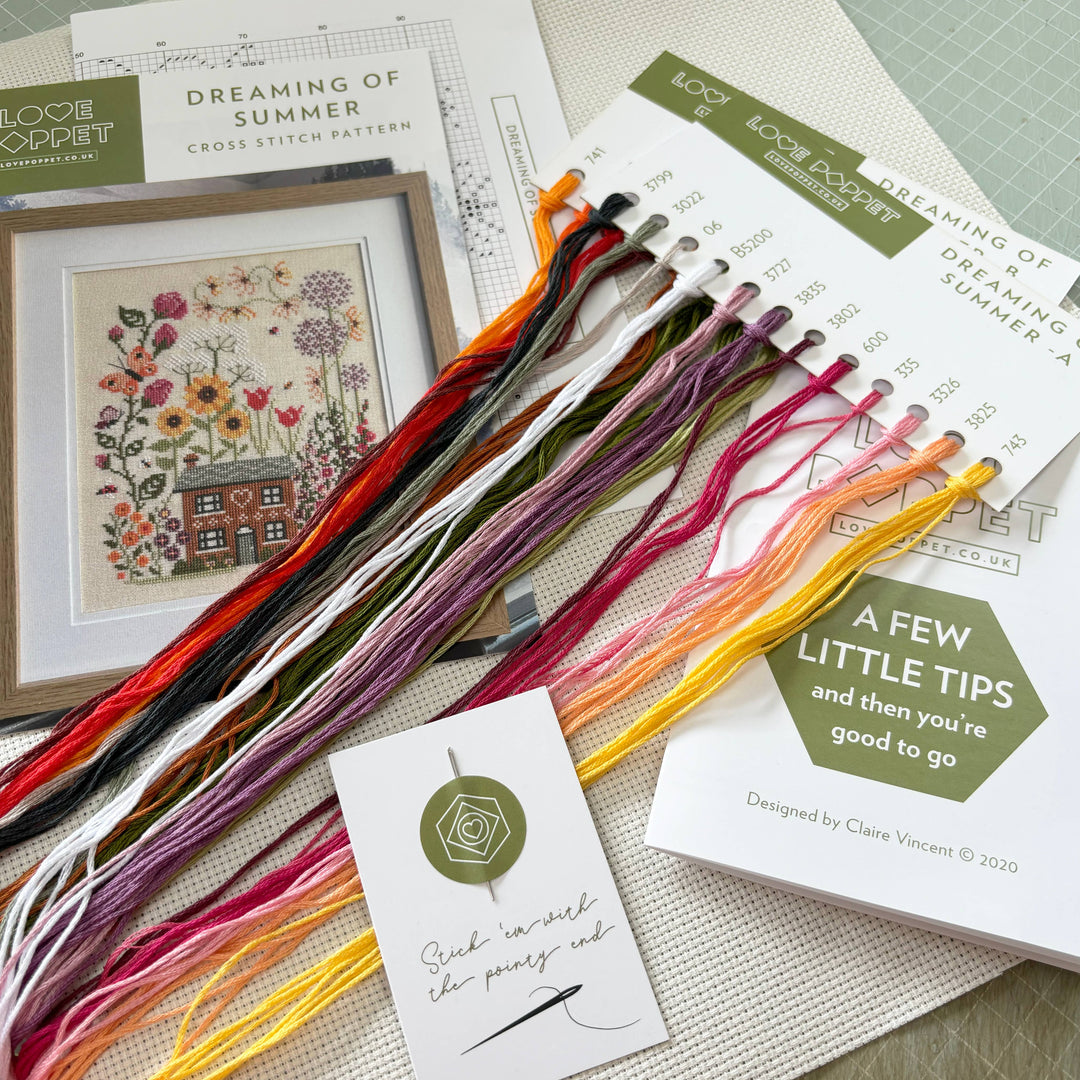 Cross stitch kit with threads, pattern, and tips on a textured surface