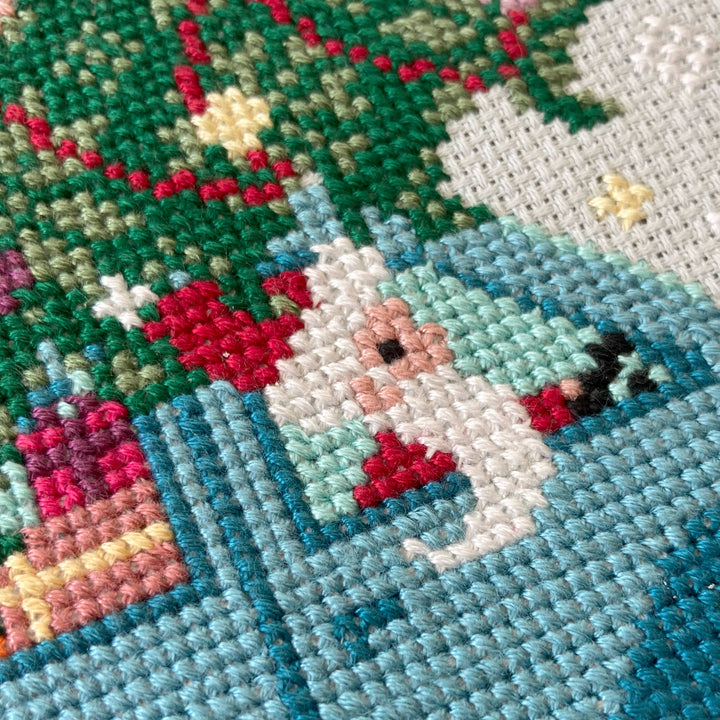 Close-up of a cross-stitched piece with a dog and festive elements.