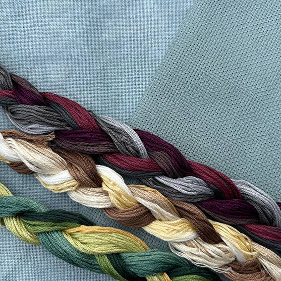 Braided yarn in various colors on a textured fabric background