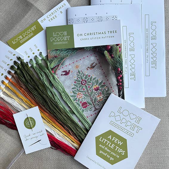 Cross stitch kit with threads and pattern sheets on a textured surface