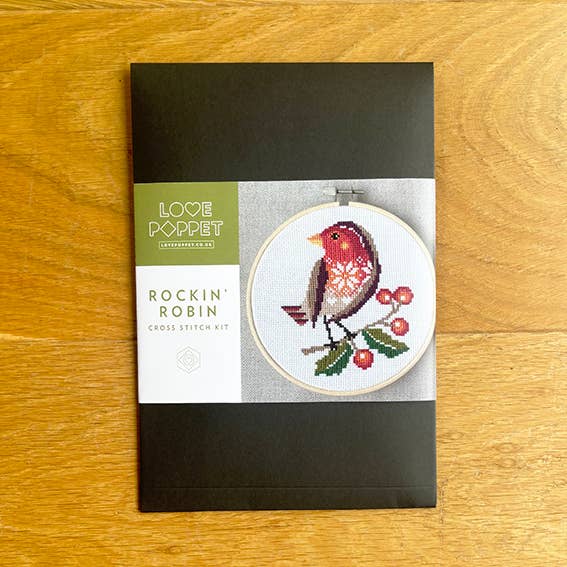 Cross stitch kit packaging with a robin design on a wooden surface