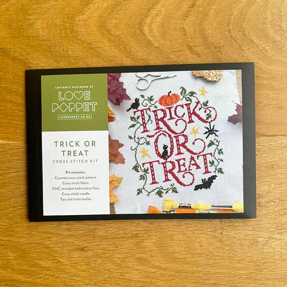 Cross stitch kit packaging with 'Trick or Treat' design on a wooden surface
