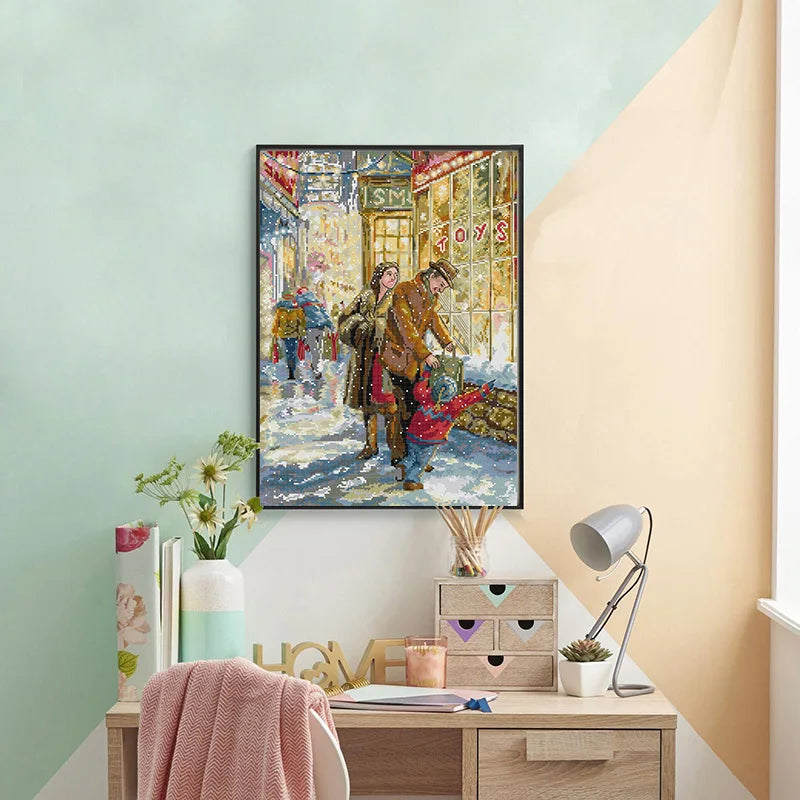 Framed artwork of a snowy street scene with people on a wall above a desk.