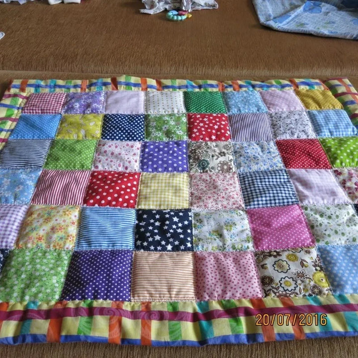 Colorful patchwork quilt on a brown surface with a date stamp.