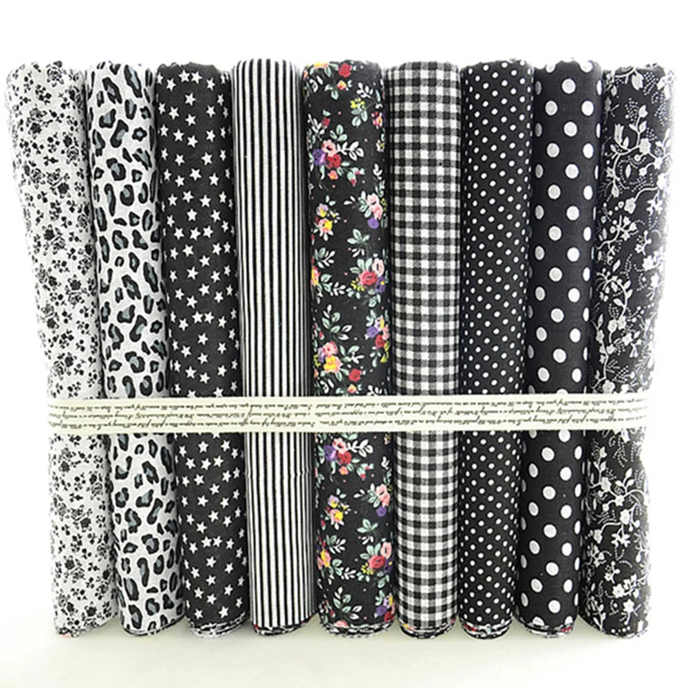 Collection of black and white patterned fabric rolls tied together on a light background