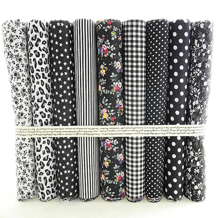 Collection of black and white patterned fabric rolls tied together on a light background