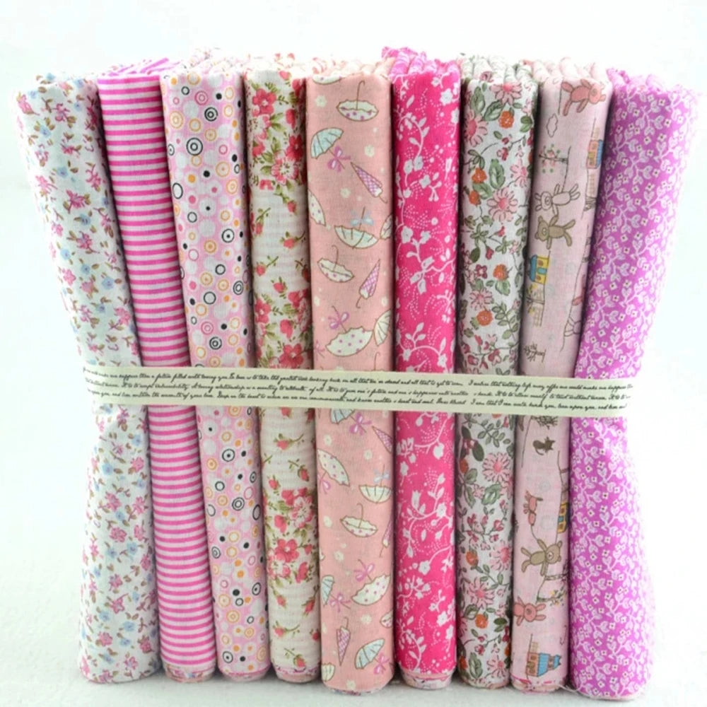 Collection of pink and floral patterned fabric rolls tied together on a white background
