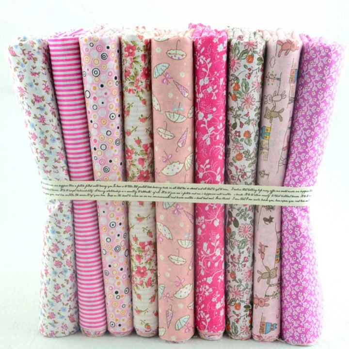 Collection of pink and floral patterned fabric rolls tied together on a white background