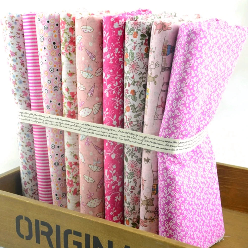 Collection of pink fabric rolls with various patterns in a wooden box.