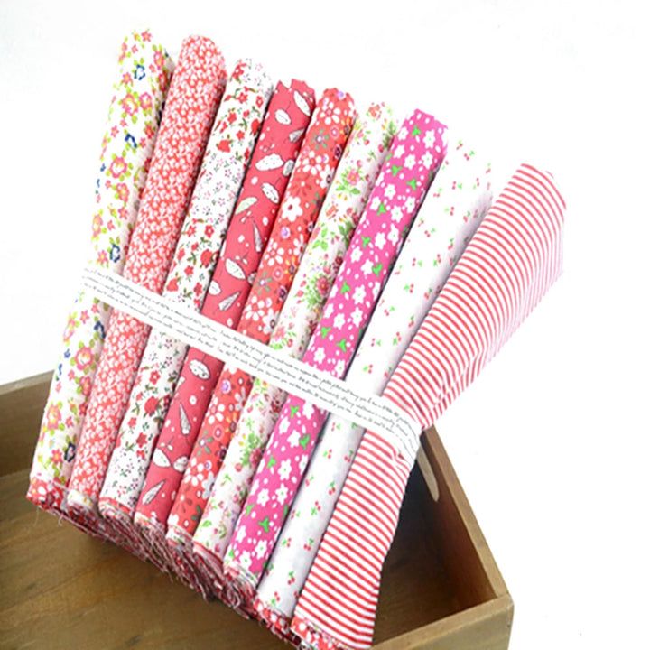 Set of pink and white fabric rolls with floral and striped patterns in a wooden box.
