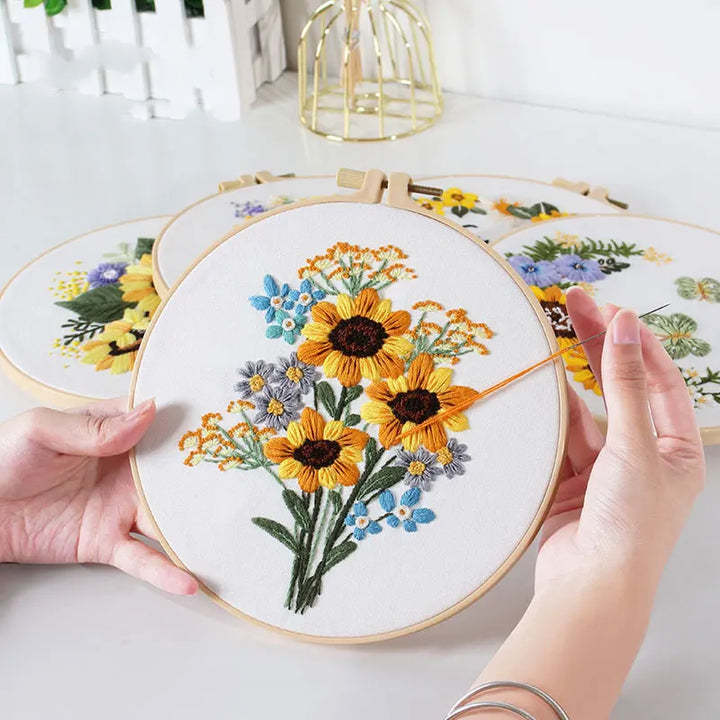 Embroidery hoop with floral design held by hands on a light background