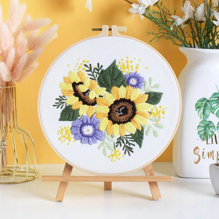 Embroidery hoop with sunflower design on a stand against a yellow background