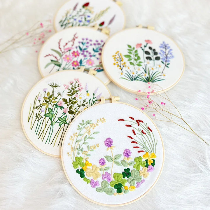 Set of embroidered floral designs in gold hoops on a soft white background