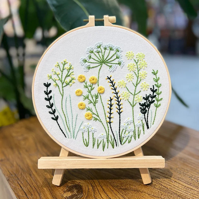 Embroidery hoop with floral design on a wooden stand, blurred background