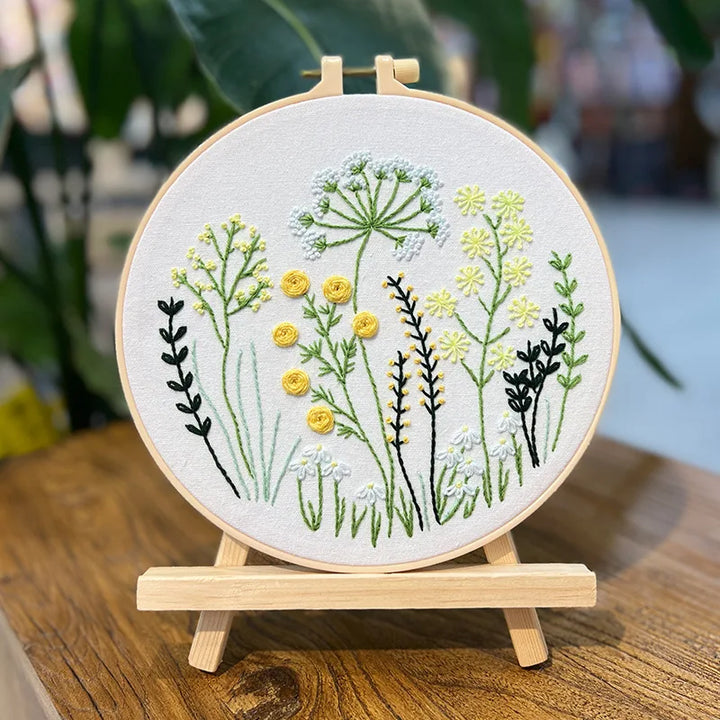 Embroidery hoop with floral design on a wooden stand, blurred background