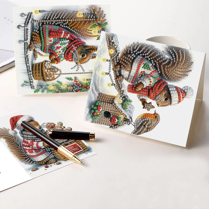 Decorative greeting cards with diamond painting designs of squirrels and a pen on a white surface.