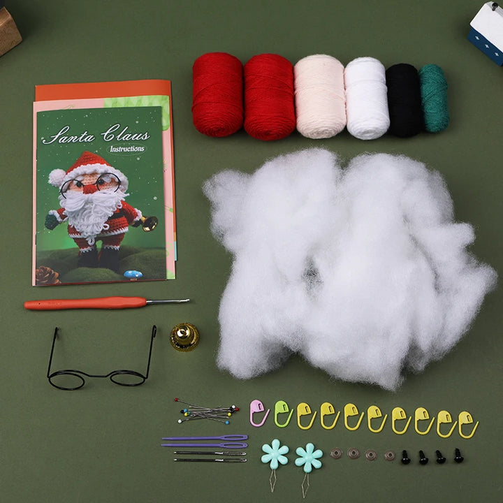 Crafting supplies including yarn, cotton, a crochet hook, and decorative items on a green surface.