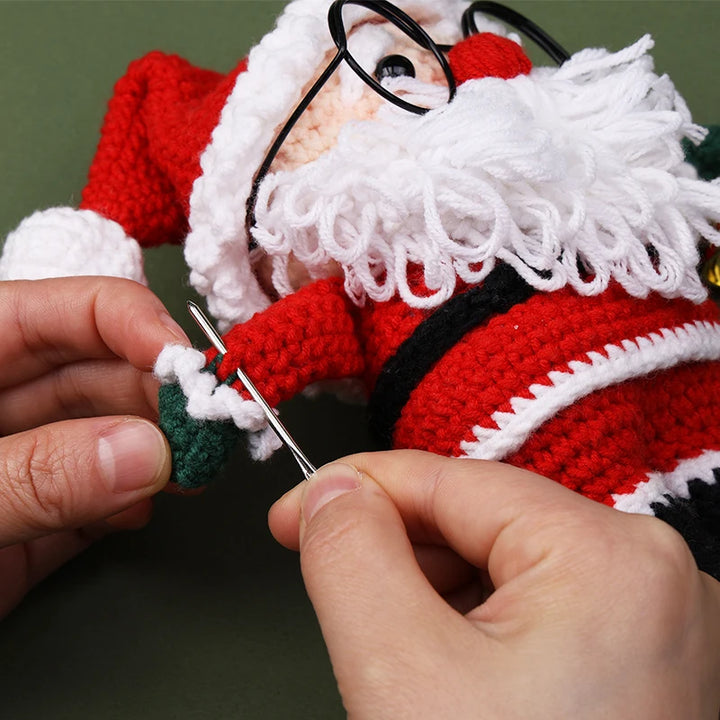 Person crocheting a red and white Santa Claus figure with a green background
