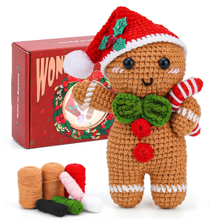 Crocheted gingerbread man toy with a red hat and candy cane, standing in front of a red box with 'Wonka' branding.