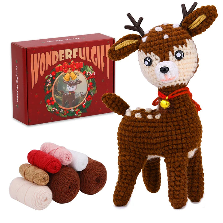 Crocheted reindeer toy with a 'WonderfulGift' box and yarn balls on a white background