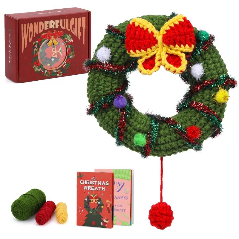 Crocheted Christmas wreath with a red bow, tinsel, and pom-poms, accompanied by yarn and pattern books on a white background.