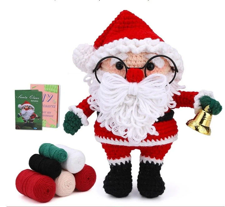 Knitted Santa Claus toy with yarn and pattern book on a white background