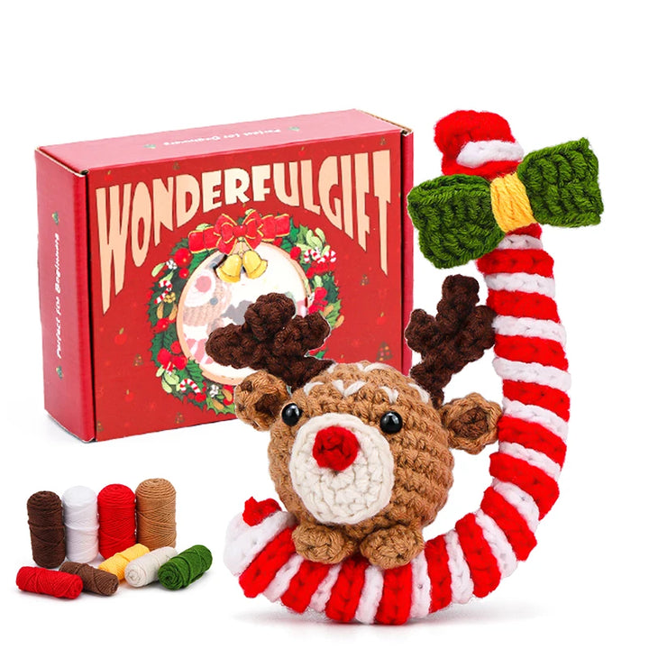 Crocheted reindeer toy with candy cane and bow, in front of a 'Wonderful Gift' box.