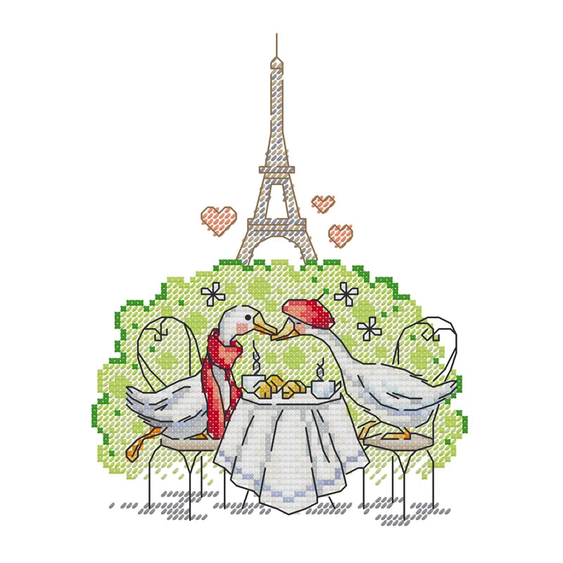 Cross-stitched design of two birds at a table with the Eiffel Tower in the background
